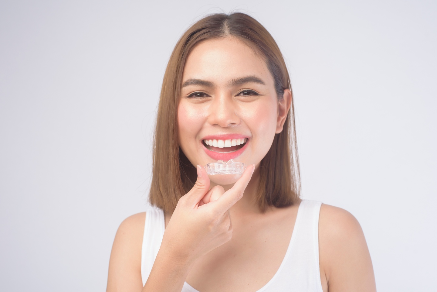 Woman holding a clear Invisalign aligner