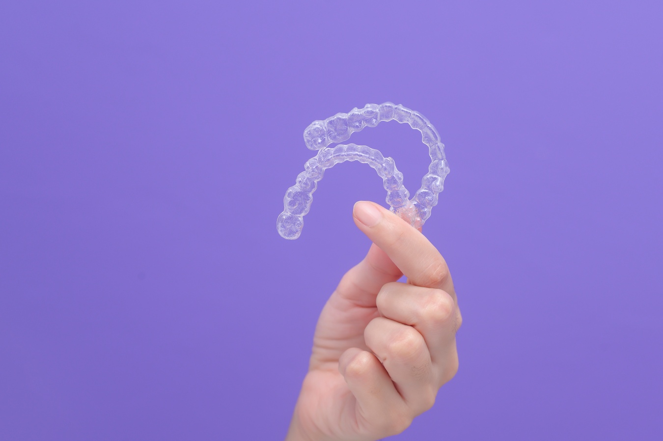 Woman holding a clear Invisalign aligner tray